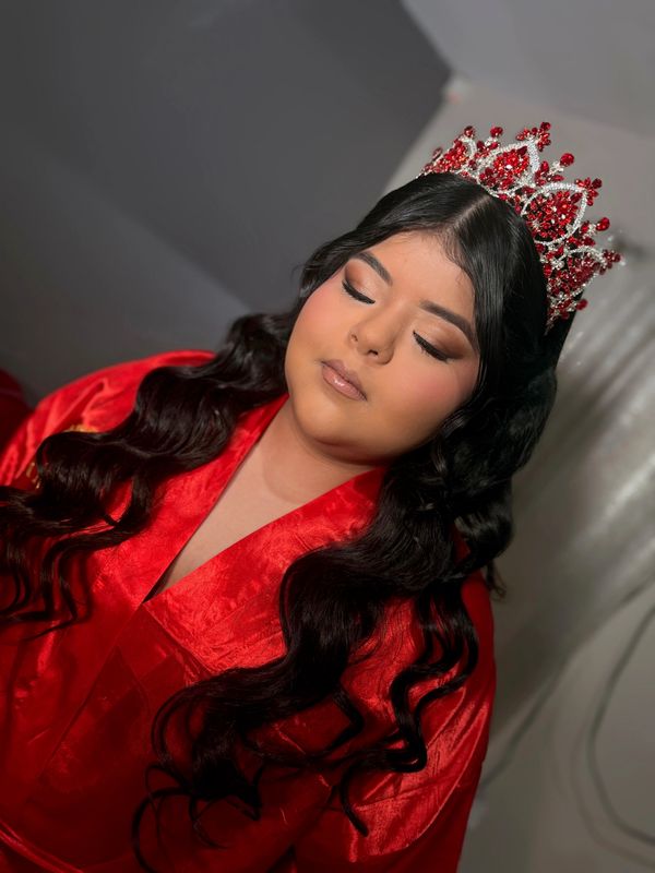 Young woman in a red robe and jeweled crown with closed eyes.