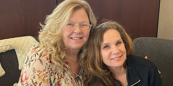 Two women smiling at a table with a Chase folder.