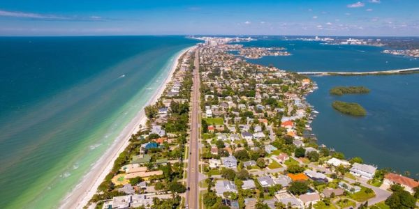 Aerial view of a coastal city with a road between the beach and a bay.