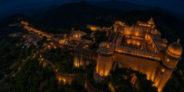 Illuminated historic fort at night in a mountainous area.