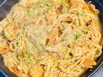 Creamy pasta with chicken and herbs in a black bowl.