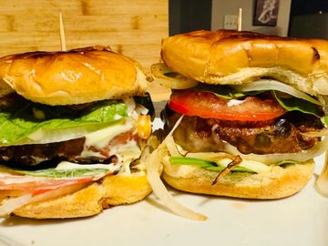 Two delicious cheeseburgers with fresh veggies and toasted buns.