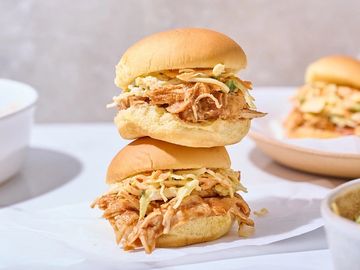 Two pulled chicken sandwiches with coleslaw on soft buns.