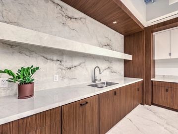Modern kitchen with wood cabinets and marble surfaces.