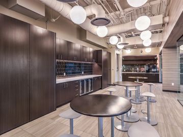 Modern office kitchen with round tables and stools.