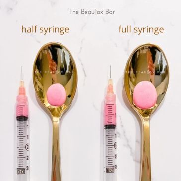 Comparison of half and full syringes next to pink pills on golden spoons.
