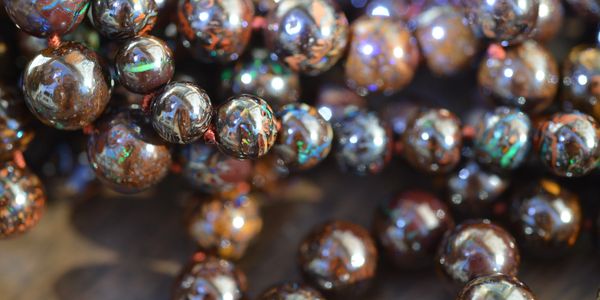 Close-up of shiny, polished beads with brown and iridescent colors on a string.