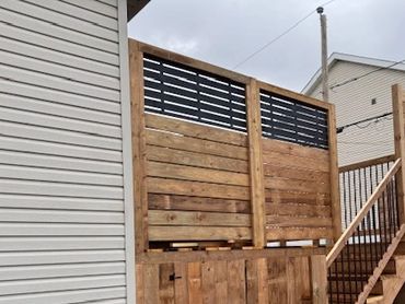 Wooden privacy fence on a deck next to a house.