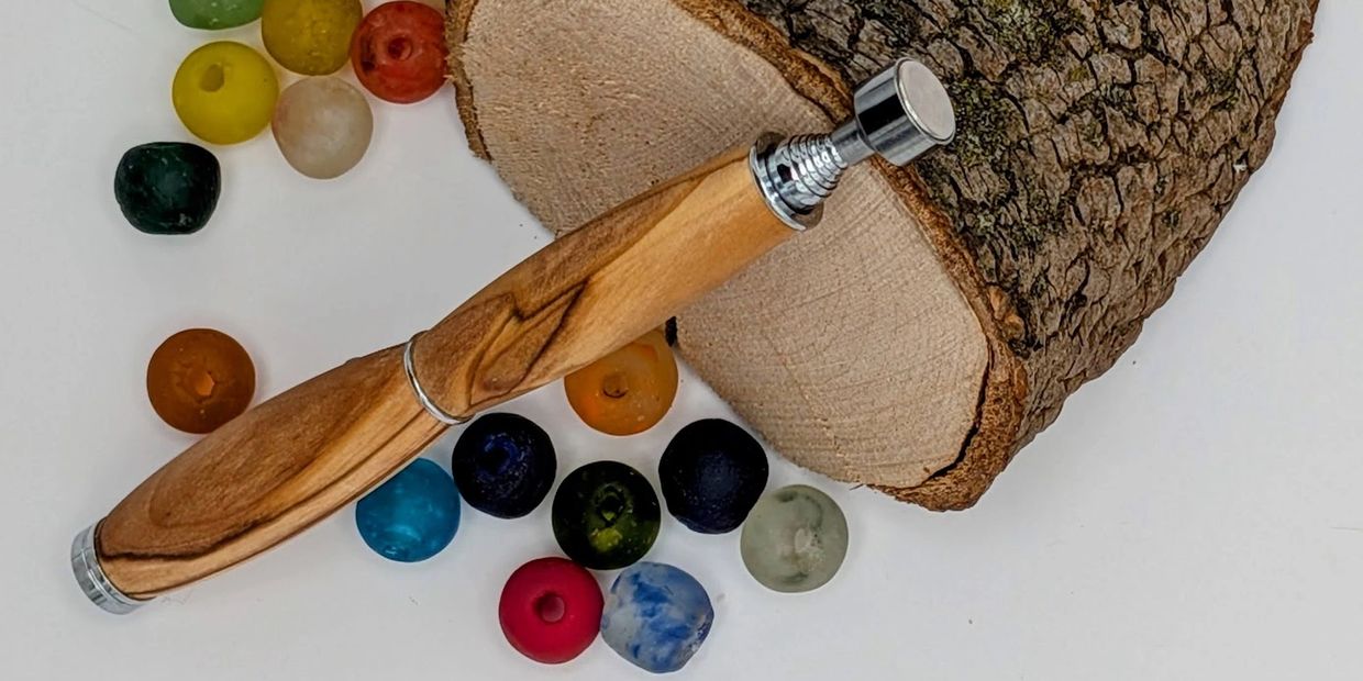 Brainspotting Pointer with colorful beads and a log slice on a white background.