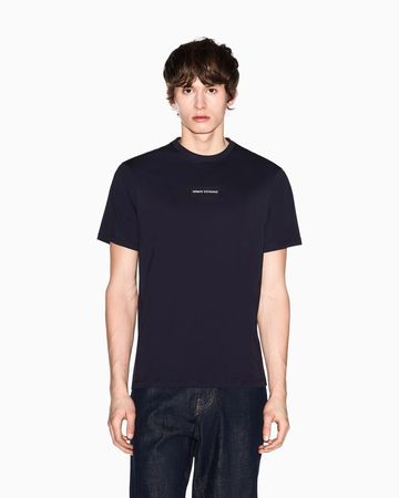 Young man wearing a black Calvin Klein t-shirt and dark jeans.