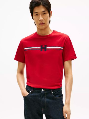 Man wearing a red t-shirt with a horizontal stripe and 'H' logo, paired with dark jeans.