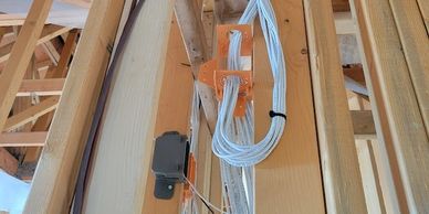 Electrical wiring neatly installed in wooden framing of a house under construction.