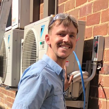 Technician installing air conditioning units outside a brick building.