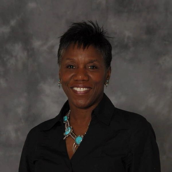 Woman with short hair smiling against a gray backdrop.