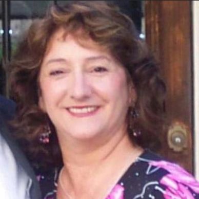 Smiling woman with curly hair and floral earrings.