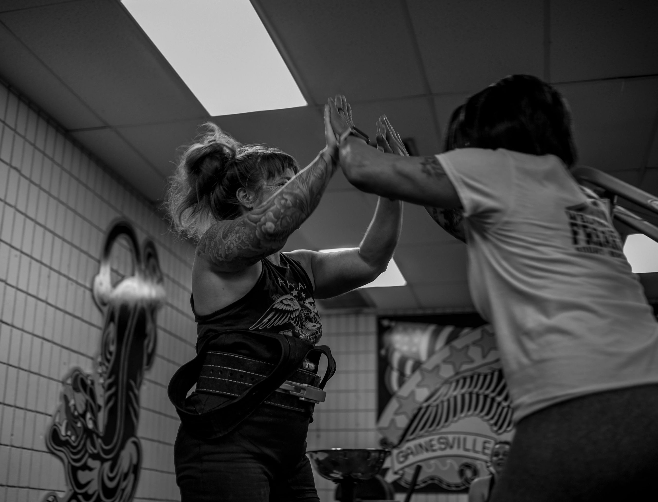 A candid of two female lifters high-fiving after a successful lift at a powerlifting competition.