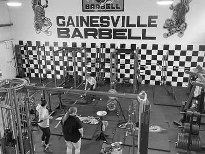 Gainesville Barbell members chatting between sets in community powerlifting space.
