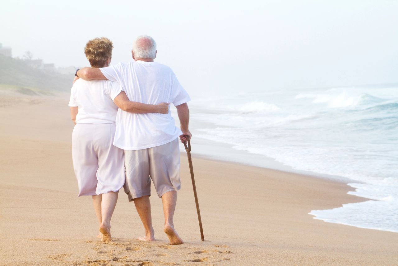 Elderly man and woman walking on beach Elderly man and woman walking on beach