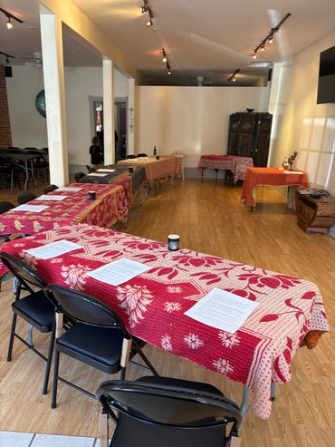 Room with tables covered in patterned cloths and chairs.  Educational event.
