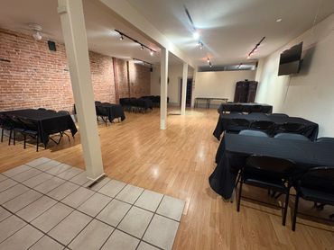 Spacious room with tables and chairs, black tablecloths.