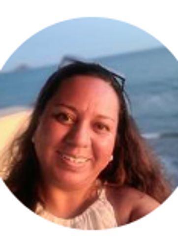 Smiling woman by the sea during sunset.