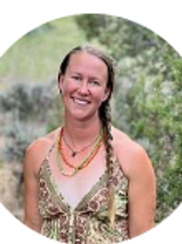 Smiling woman with a braid in a patterned dress outdoors.