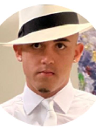 Man in white hat and shirt with serious expression.