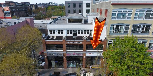 Aerial view of a brick building with shops and a large arrow sign.