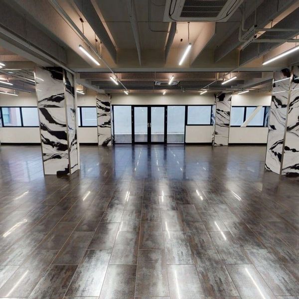 Spacious modern room with marble-patterned pillars and dark wood flooring.