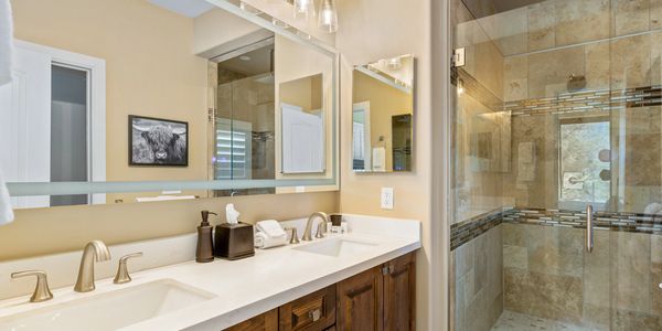 Modern bathroom with double sinks and glass shower enclosure.