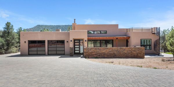 Modern southwestern-style house with stone accents and large driveway.