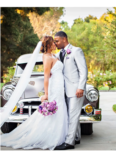 Newlyweds kissing in front of a vintage car