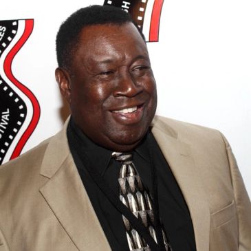 Smiling man in a beige suit at an event.