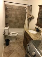 Small bathroom with bathtub, toilet, and washer.
