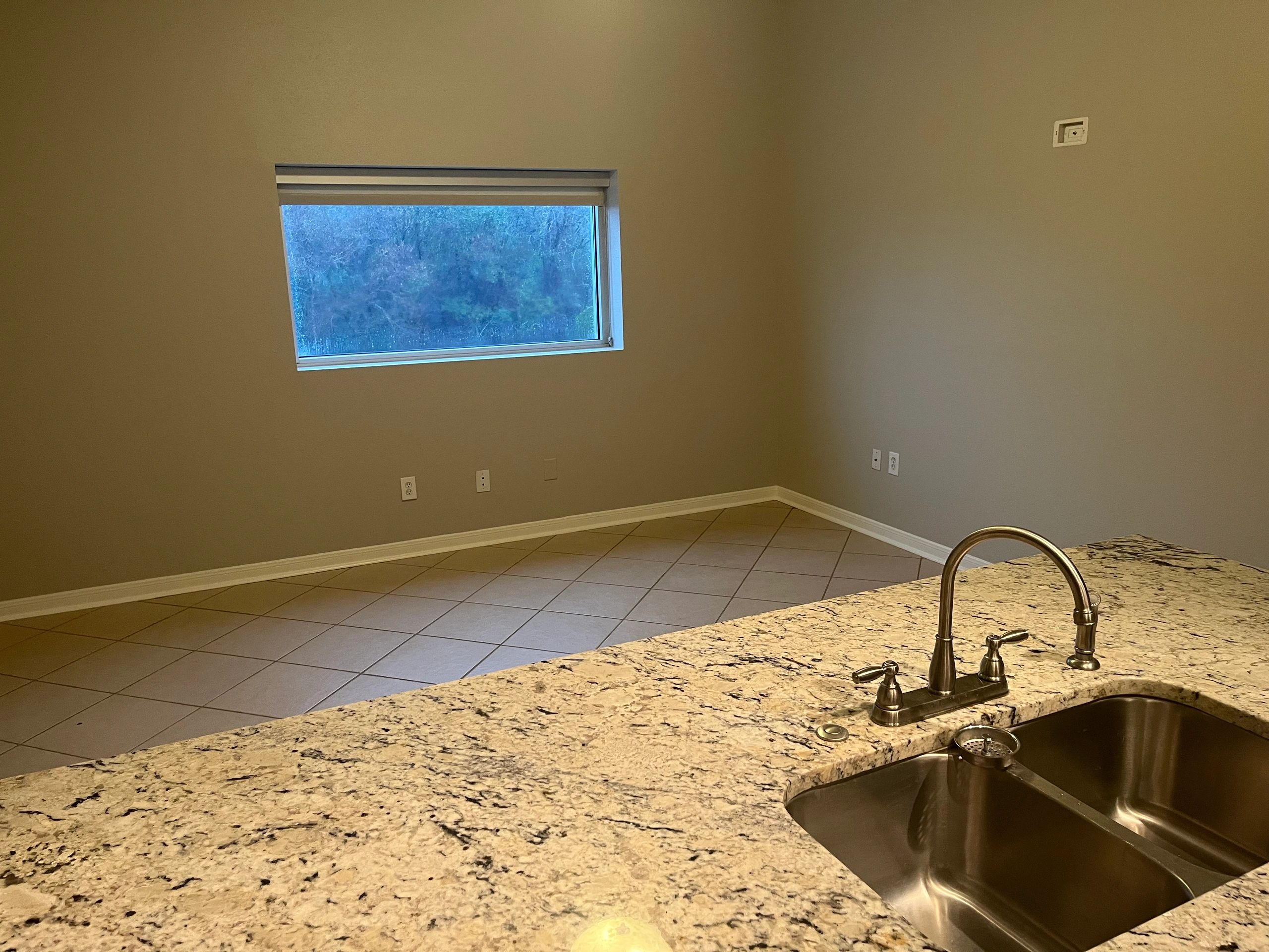 Empty room with a window and granite countertop sink.