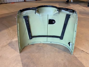 Car hood placed upside down on a floor.