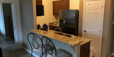 Modern kitchen with granite countertop and metal bar stools.