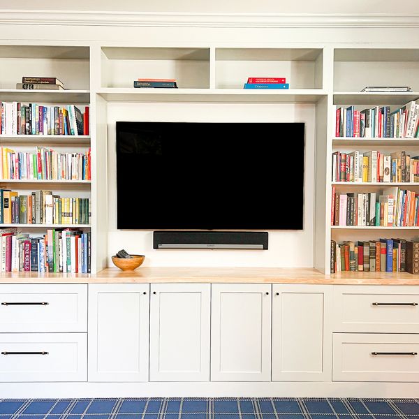 Modern built-in white bookshelf with TV and soundbar in a cozy living room.