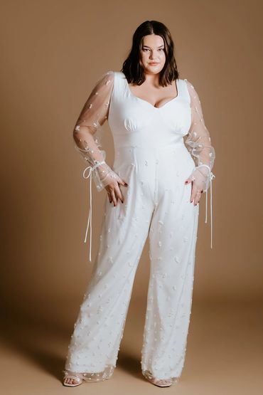 Romantic bridal jumpsuit in ivory that features an illusion pearl sleeves and wide leg trousers.