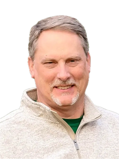 Middle-aged man smiling in a light gray zip-up sweater.
