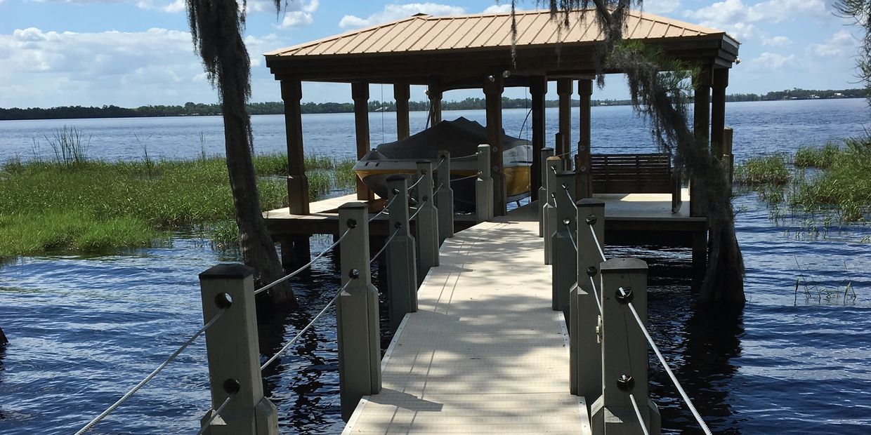 Covered dock with boat on a lake on a sunny day.