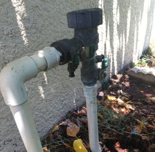 Outdoor water faucet attached to a wall with pipes.
