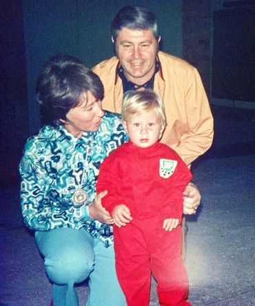 Little Jason with mother and father in red racing suit. 