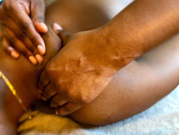 A black woman having a shoulder massaged