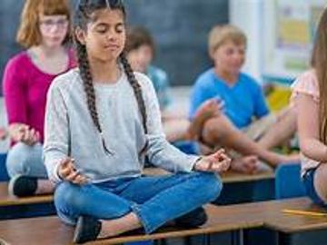children sitting on top of desks in a yoga pose