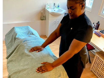 black woman laying hands on towel over person laying down