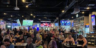 Packed sports bar at That Place Bar & Grill with fans watching games on big-screen TVs.