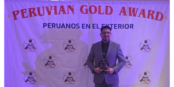 Man in a gray suit holding a Peruvian Gold Award plaque.