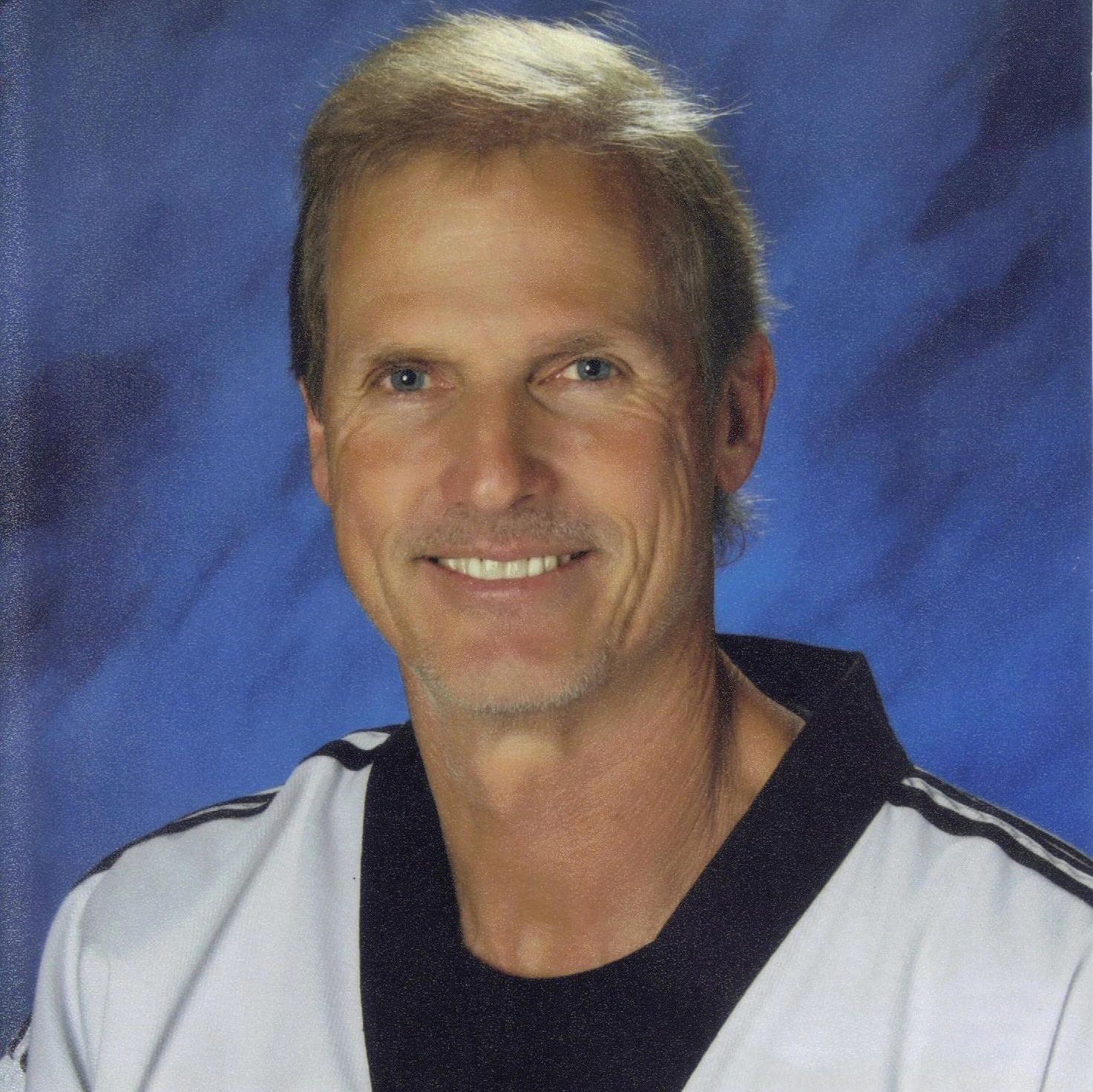 Portrait of a smiling man with light hair and blue eyes.