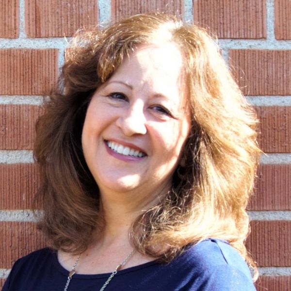 Person smiling against a brick wall.